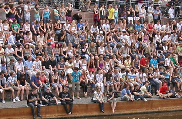 Sehr viele Menschen sitzen eng gedrängt nebeneinander