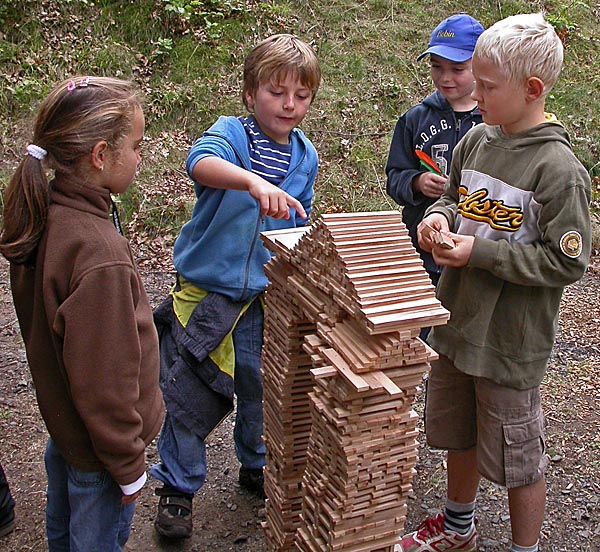 Kinder stehen um Turm aus Holzteilen